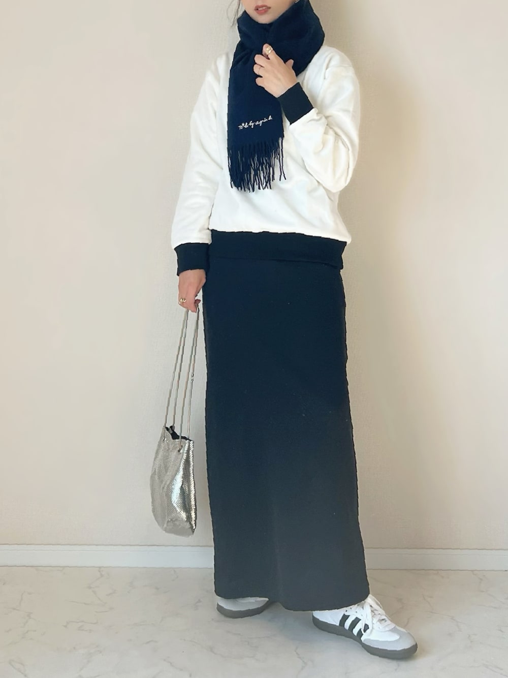ホワイト系のスウェット、ブラック系のスカート、ホワイト系のスニーカーを着用したレディースの秋コーディネートの1枚目の写真