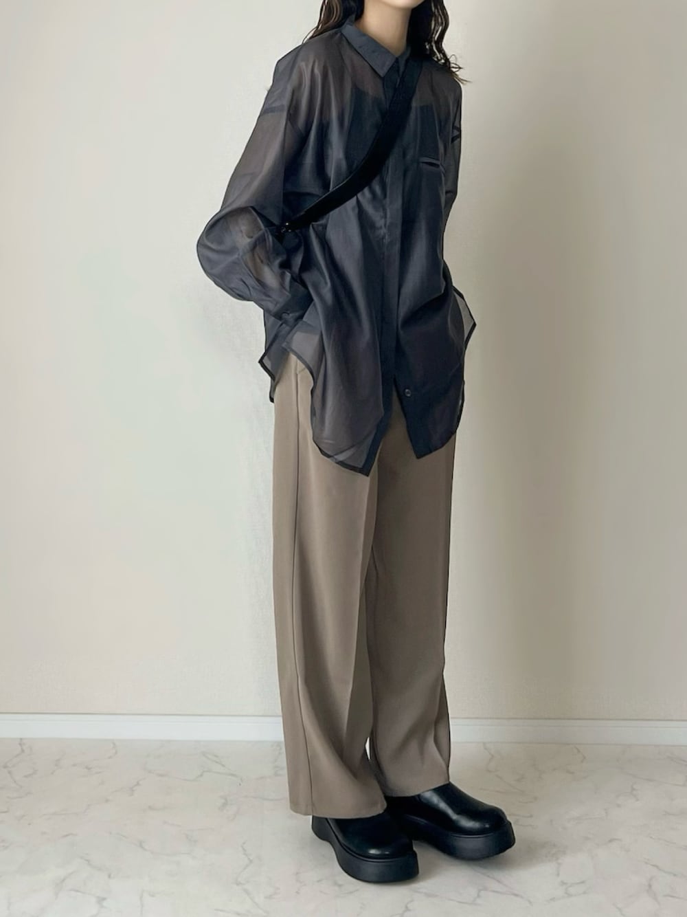 ベージュ系のスラックス、ブラック系のショルダーバッグ、ブラック系のスリッポンを着用したレディースの春コーディネートの1枚目の写真