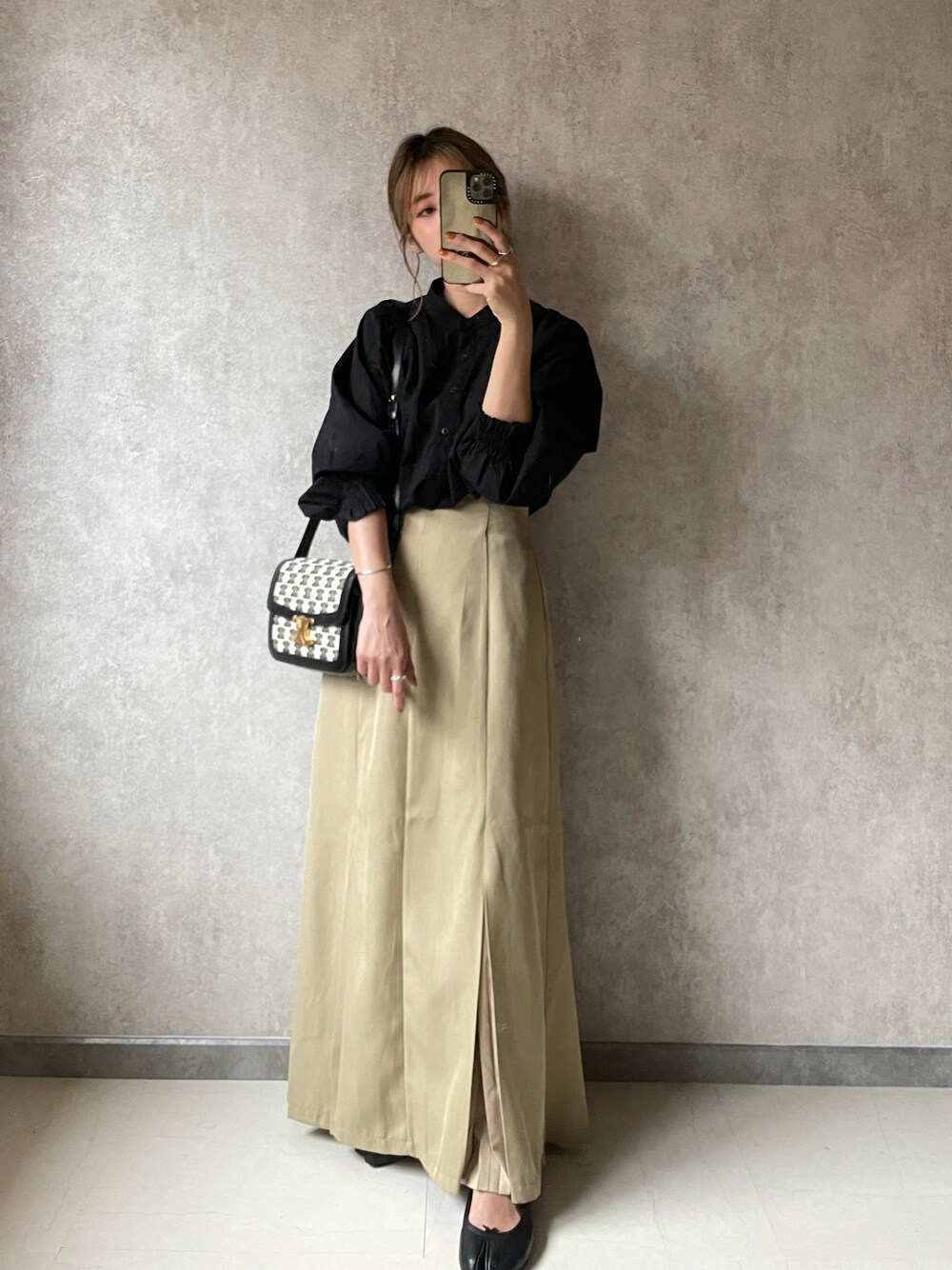 ベージュ系のスカート、ブラック系のトップス、ブラック系のバレエシューズを着用したレディースの夏コーディネートの1枚目の写真