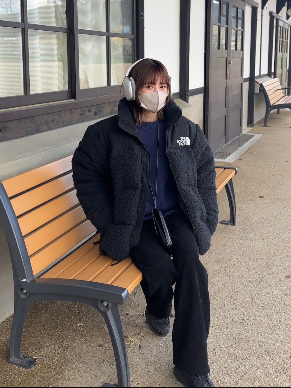 ブラック系のジャケット/アウター、ブルー系のニット/セーター、ブラック系のスニーカーを着用したレディースの冬コーディネートの1枚目の写真