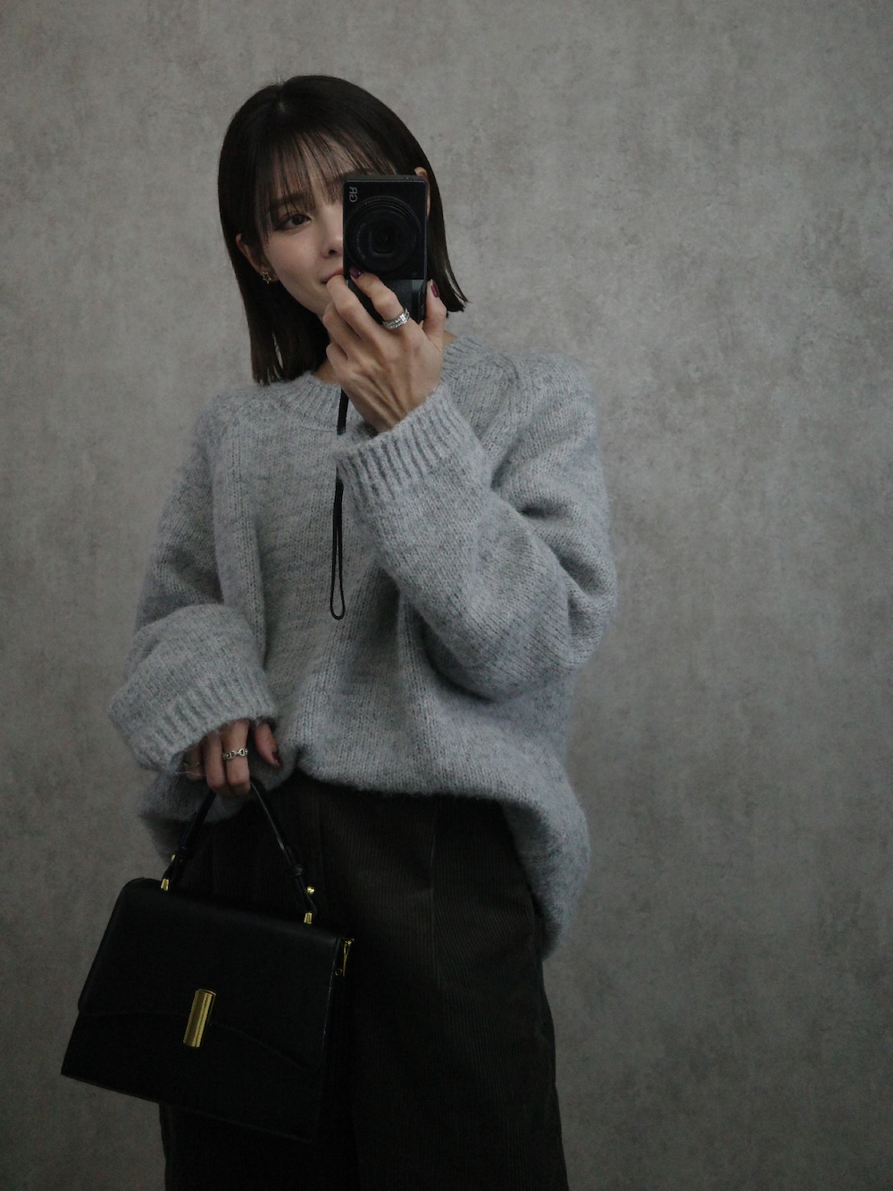 グレー系のニット/セーター、ブラック系のショルダーバッグを着用したレディースの秋コーディネートの1枚目の写真