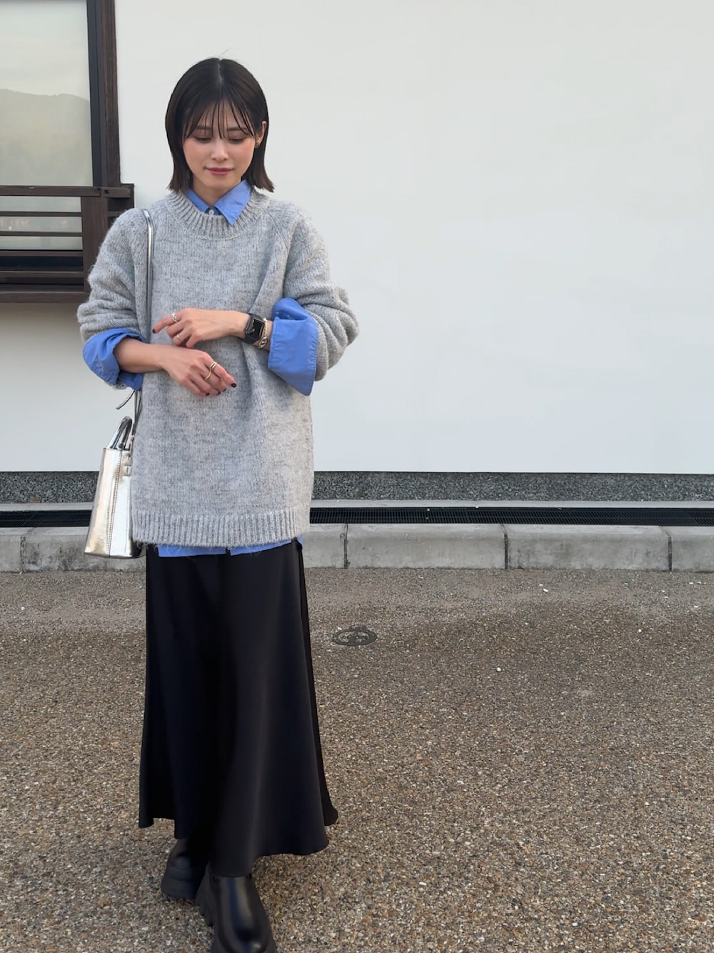 グレー系のニット/セーター、ブラック系のスカートを着用したレディースの秋コーディネートの1枚目の写真