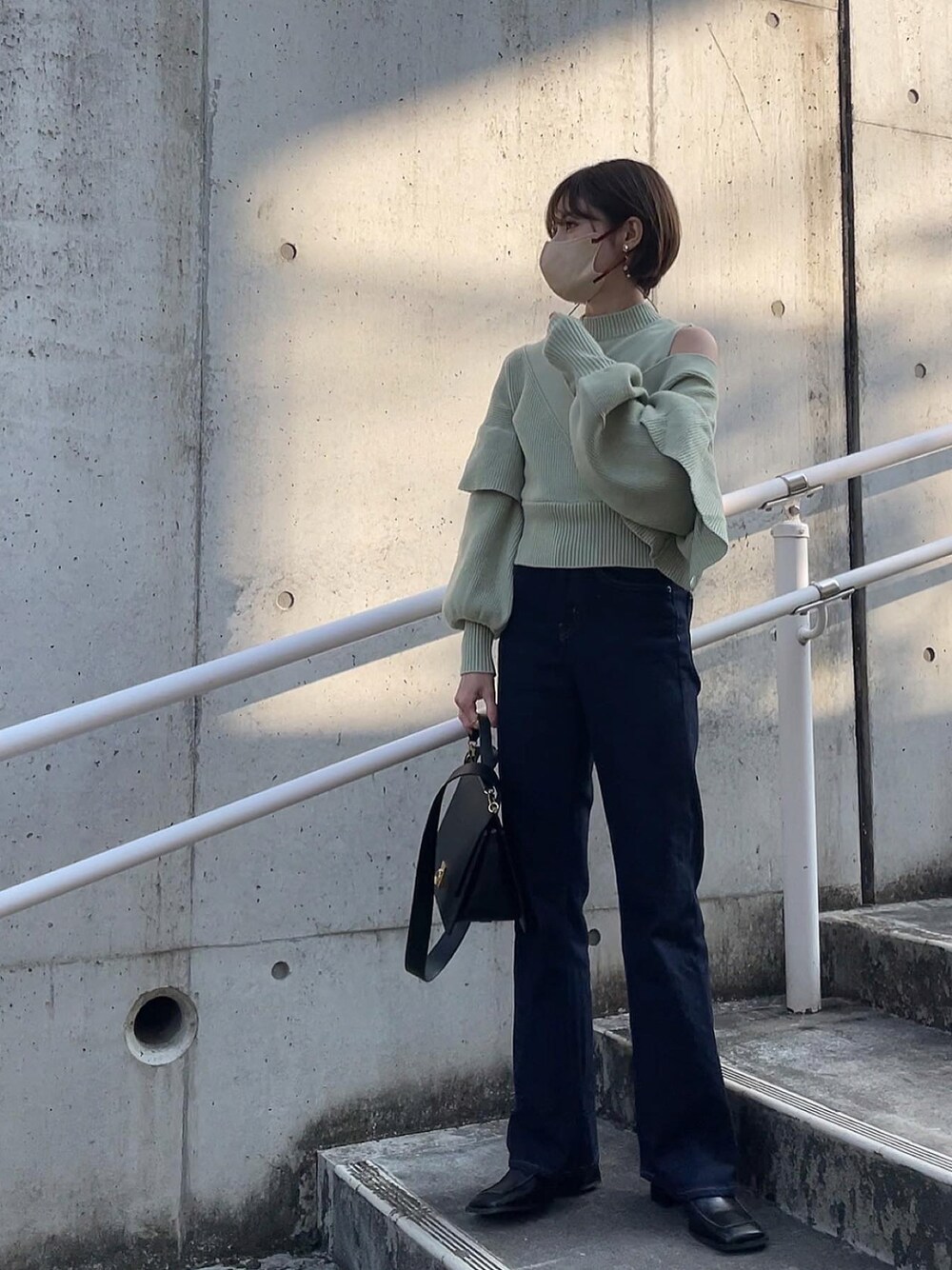 グリーン系のニット/セーター、ブラック系のブーツを着用したレディースの冬コーディネートの1枚目の写真