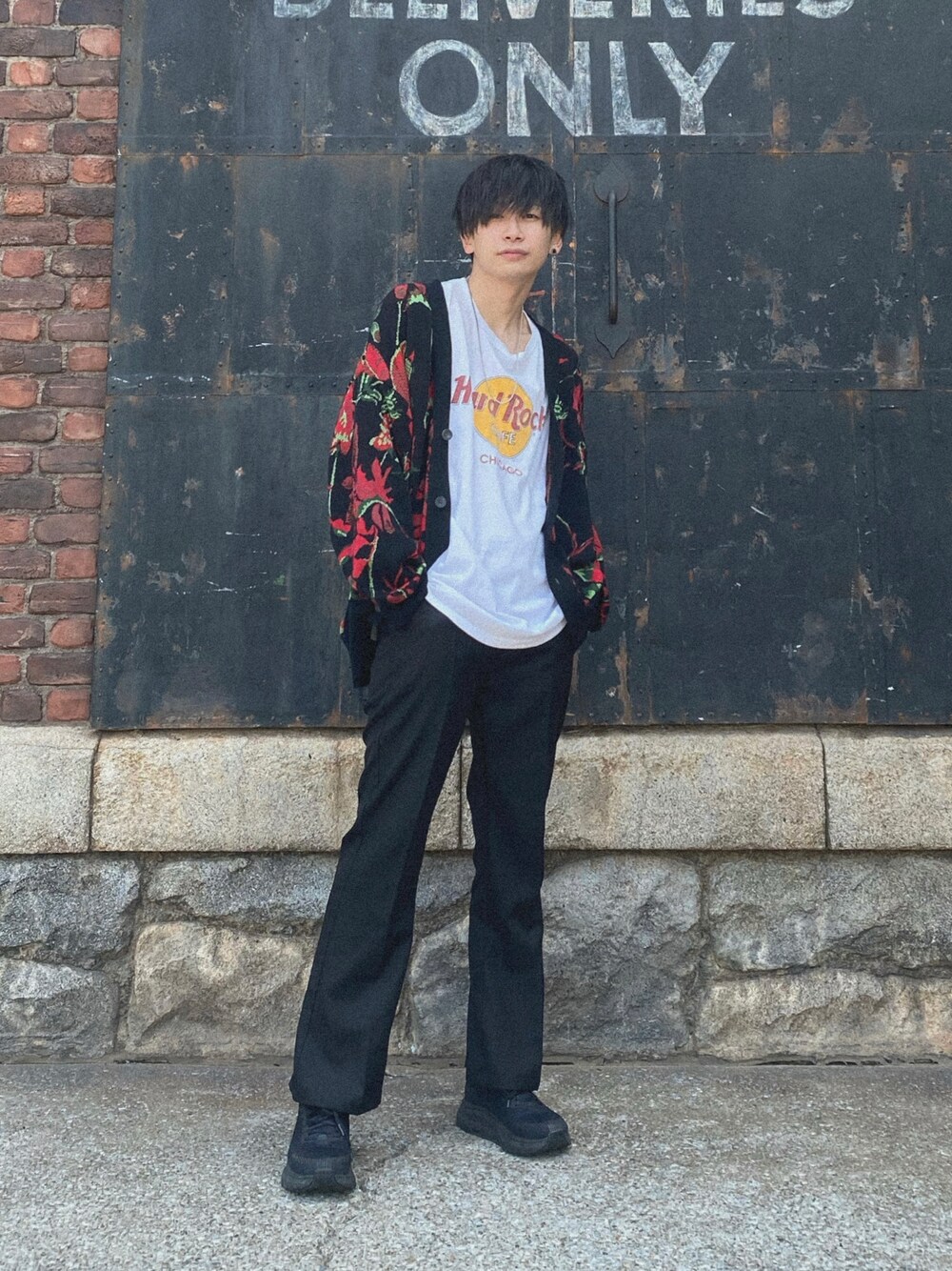 レッド系のカーディガン/ボレロ、ホワイト系のTシャツ/カットソー、ブラック系のスラックスを着用したメンズの春コーディネートの1枚目の写真