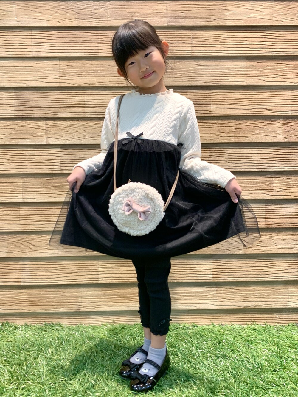 ピンク系のダウンジャケット/コート、ベージュ系のワンピース、ブラック系のその他パンツを着用したキッズの冬コーディネートの1枚目の写真