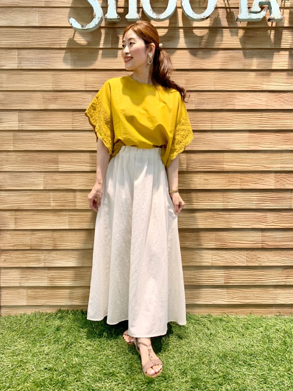 イエロー系のシャツ/ブラウス、ホワイト系のスカート、ベージュ系のサンダルを着用したレディースの夏コーディネートの1枚目の写真