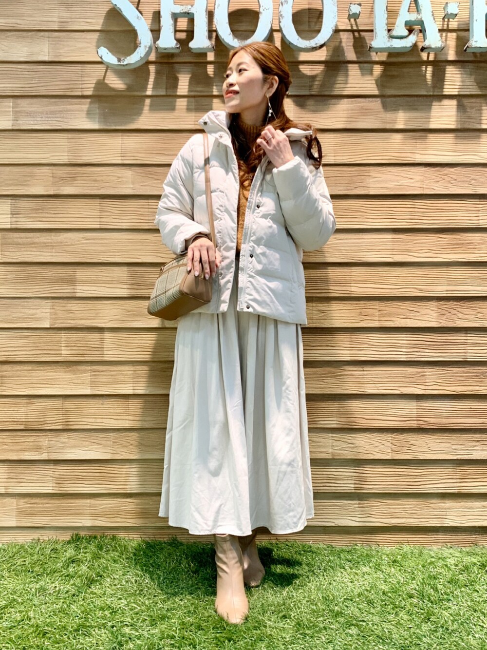 ホワイト系のダウンジャケット/コート、オレンジ系のニット/セーター、ホワイト系のスカートを着用したレディースの冬コーディネートの1枚目の写真