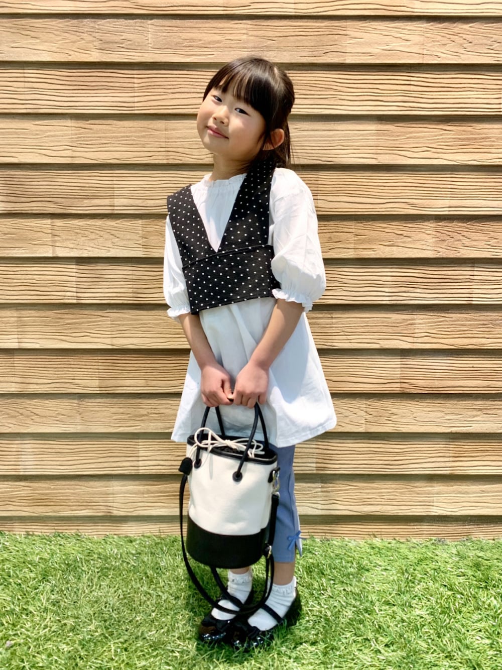 ブラック系のワンピース、ブルー系のその他パンツ、ブラック系のハンドバッグを着用したキッズの春コーディネートの1枚目の写真