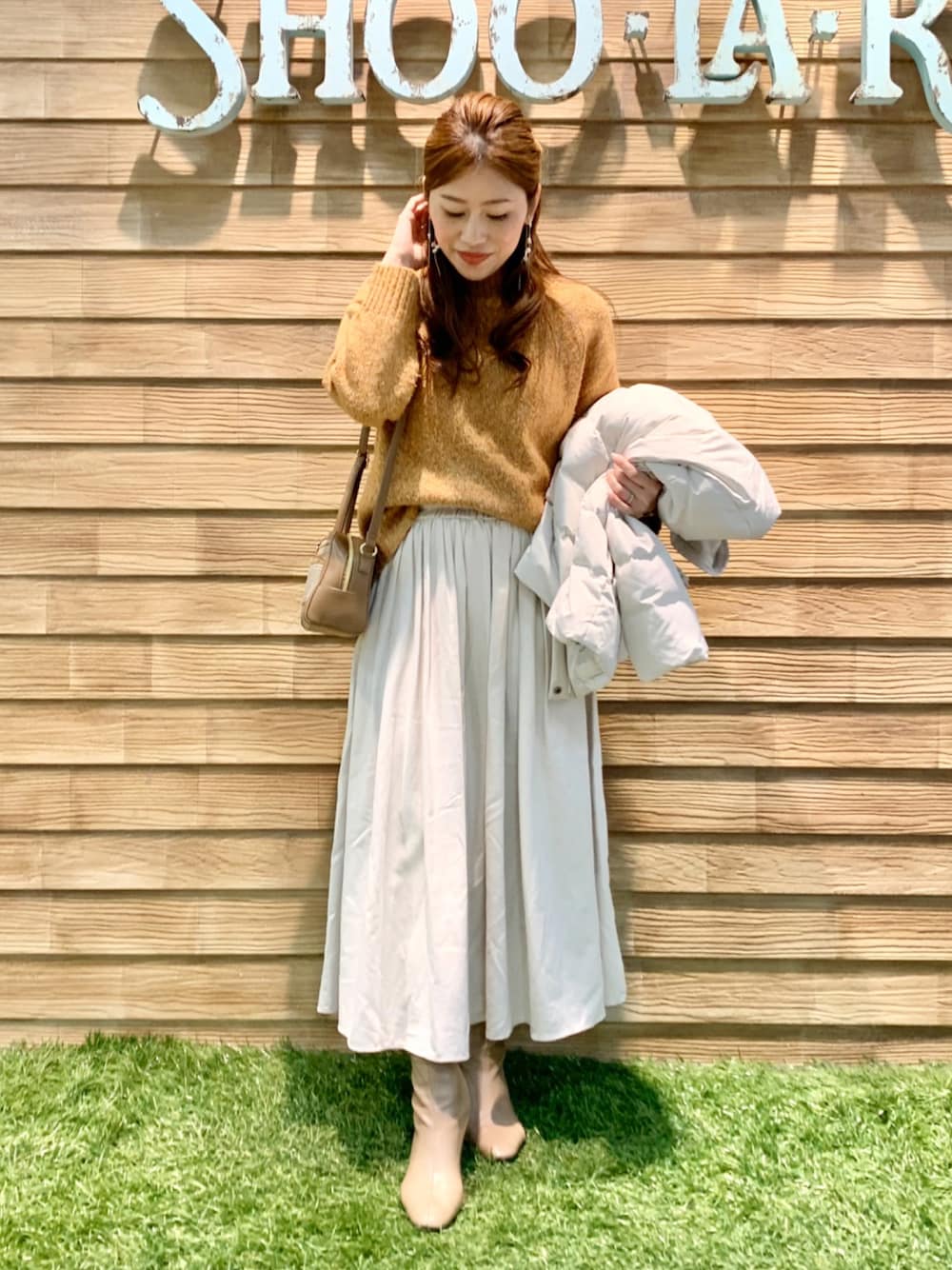 ホワイト系のダウンジャケット/コート、オレンジ系のニット/セーター、ホワイト系のスカートを着用したレディースの冬コーディネートの1枚目の写真