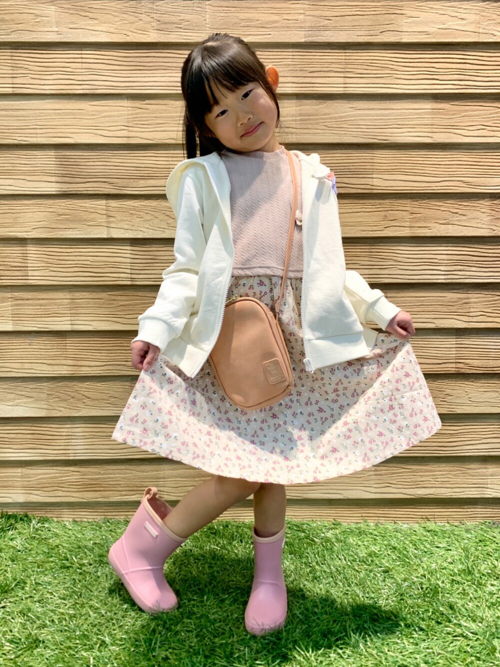 ホワイト系のパーカー、ピンク系のワンピース、ピンク系のショルダーバッグを着用したキッズの春コーディネートの1枚目の写真