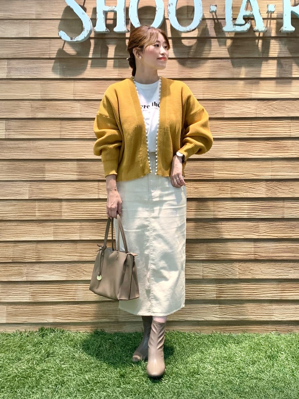 イエロー系のカーディガン/ボレロ、ホワイト系のTシャツ/カットソー、ホワイト系のスカートを着用したレディースの冬コーディネートの1枚目の写真