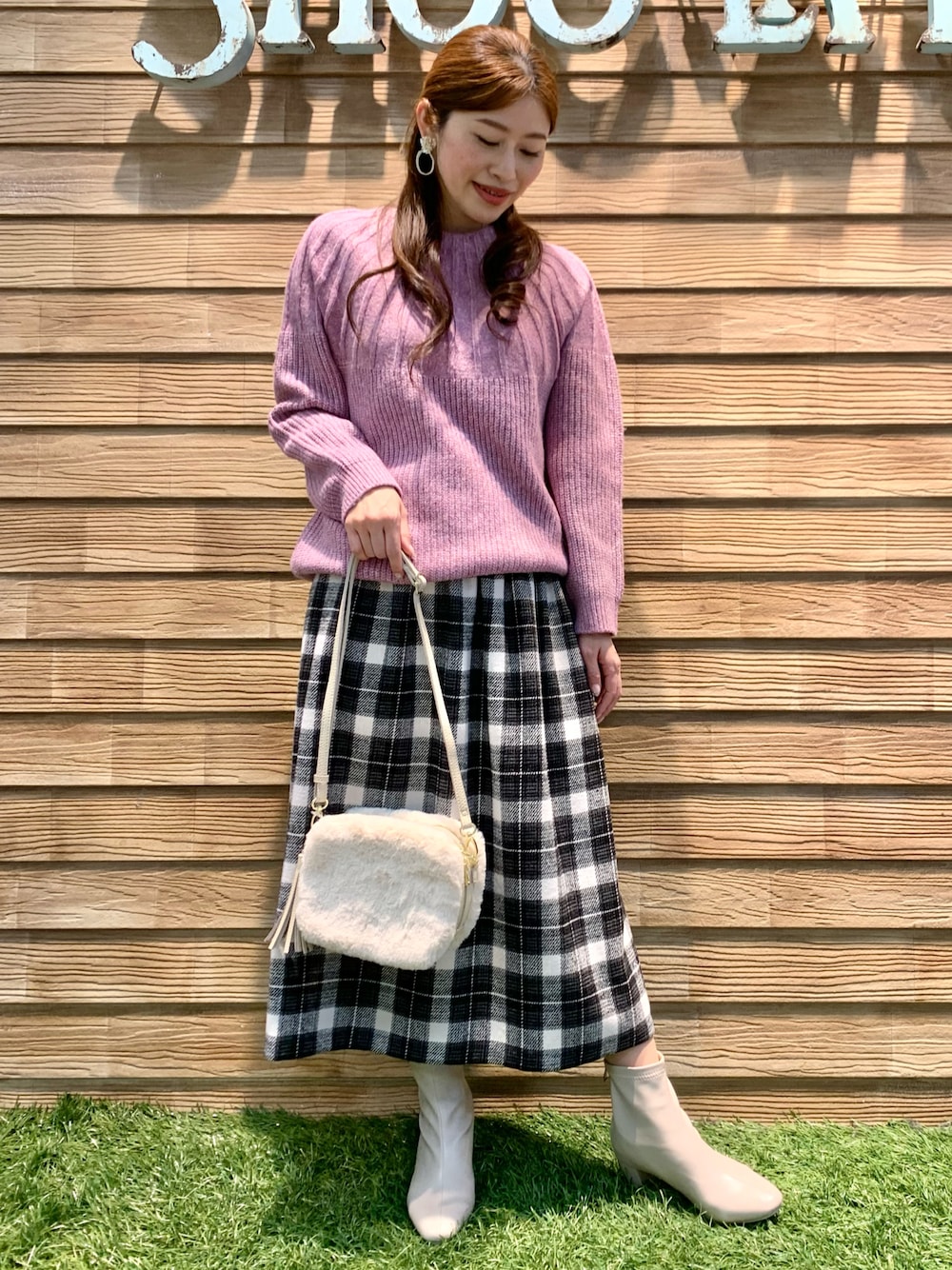 ピンク系のニット/セーター、グレー系のスカート、ホワイト系のショルダーバッグを着用したレディースの冬コーディネートの1枚目の写真