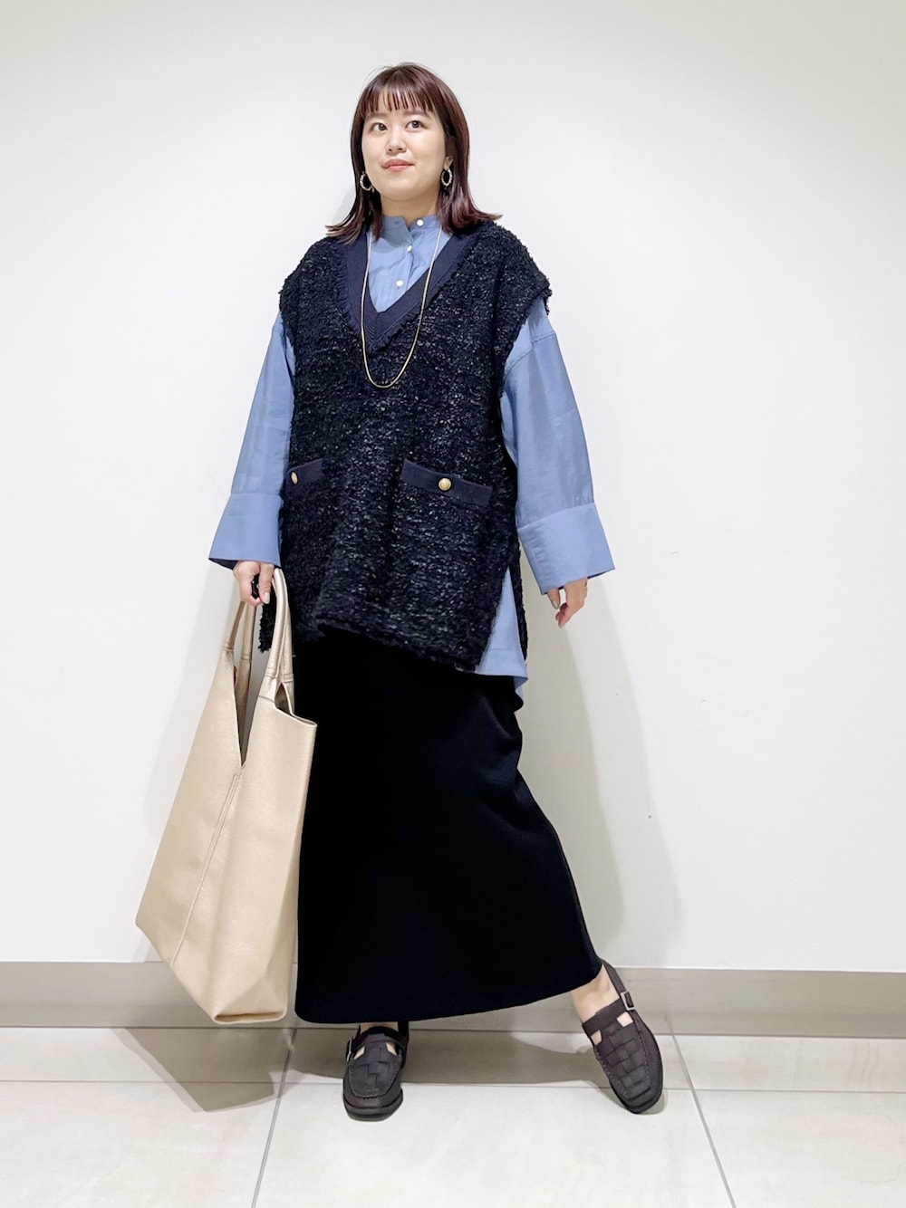ブルー系のシャツ/ブラウス、ブラック系のスカート、ゴールド系のトートバッグを着用したレディースの秋コーディネートの1枚目の写真