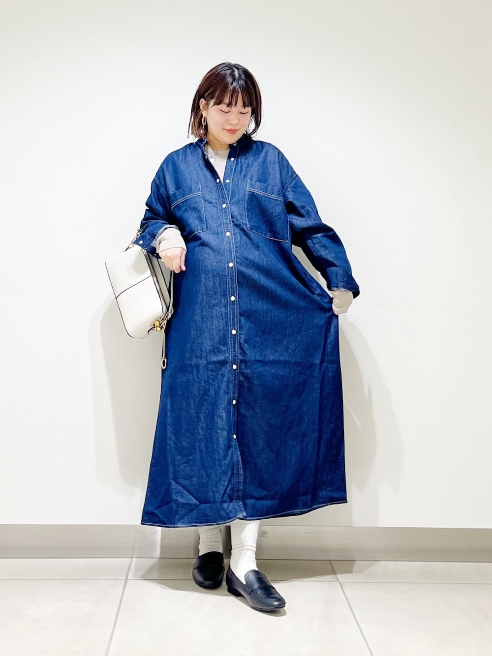 ブルー系のワンピース、ベージュ系のニット/セーター、ホワイト系のショルダーバッグを着用したレディースの秋コーディネートの1枚目の写真