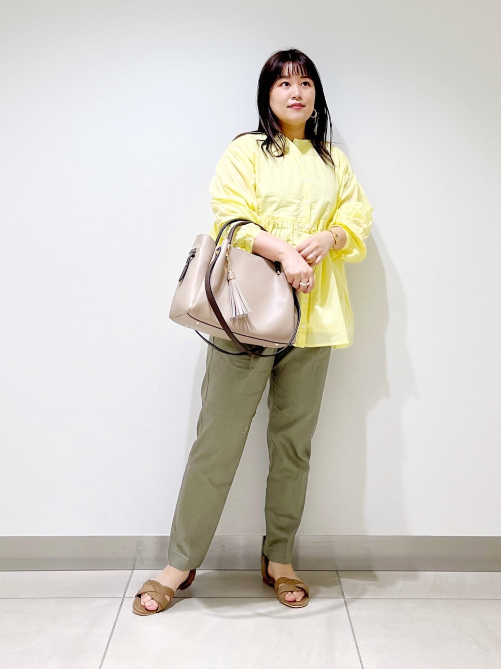 イエロー系のシャツ/ブラウス、グリーン系のその他パンツ、ベージュ系のトートバッグを着用したレディースの春コーディネートの1枚目の写真