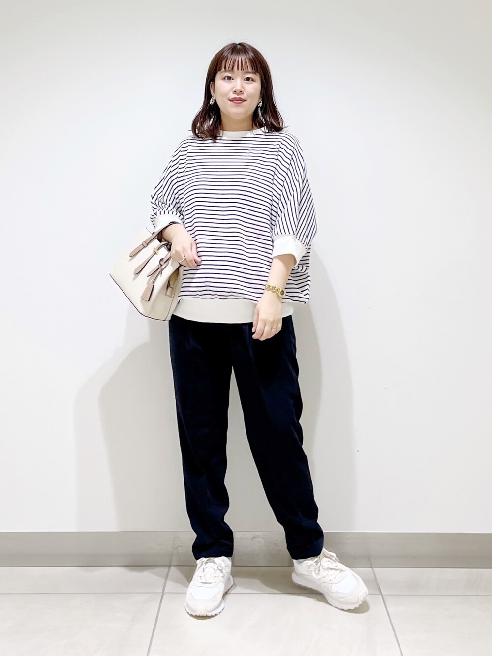 ホワイト系のTシャツ/カットソー、ブルー系のパンツ、ホワイト系のハンドバッグを着用したレディースの秋コーディネートの1枚目の写真