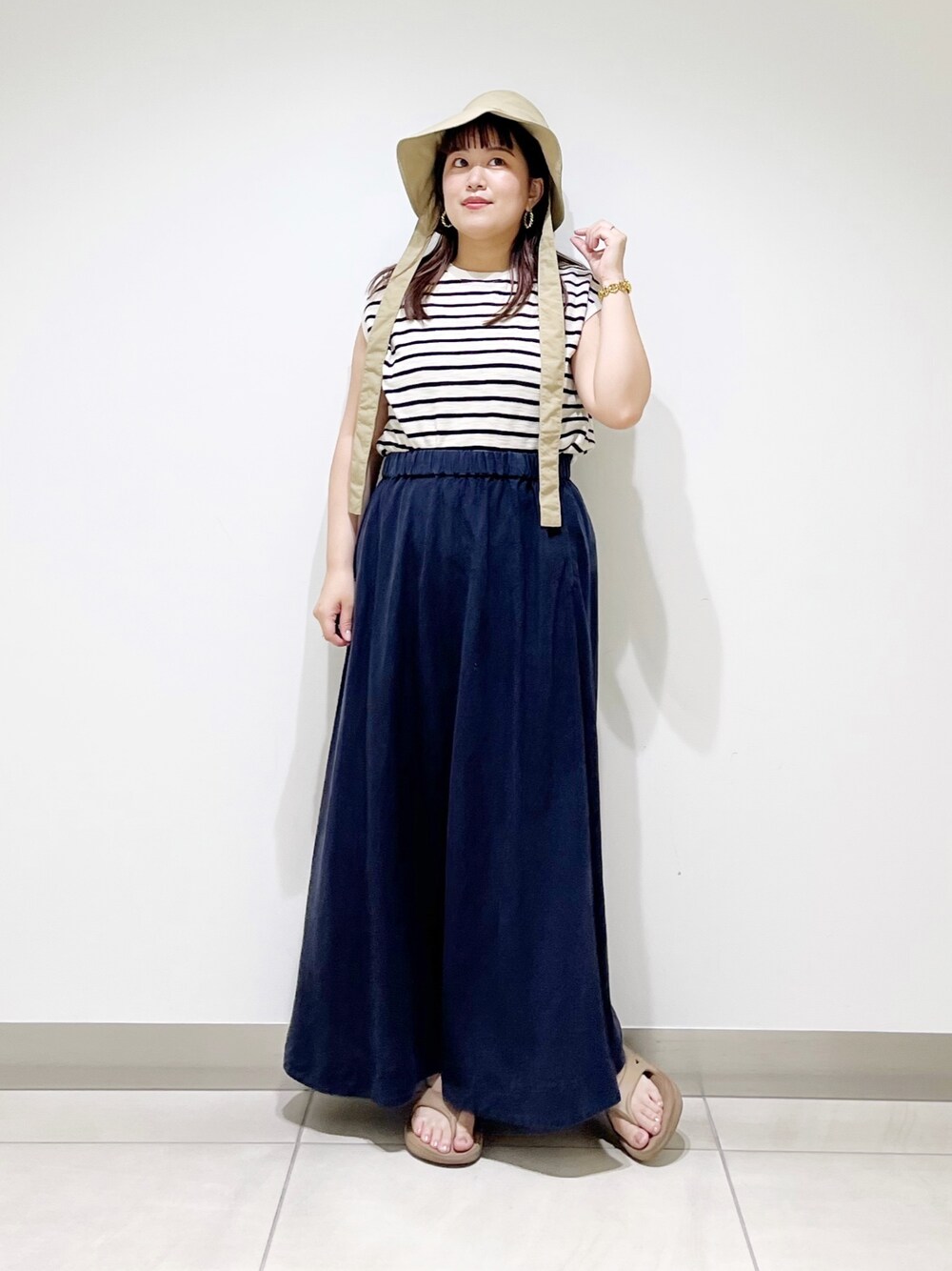 ベージュ系のTシャツ/カットソー、ブルー系のスカート、ベージュ系のサンダルを着用したレディースの夏コーディネートの1枚目の写真