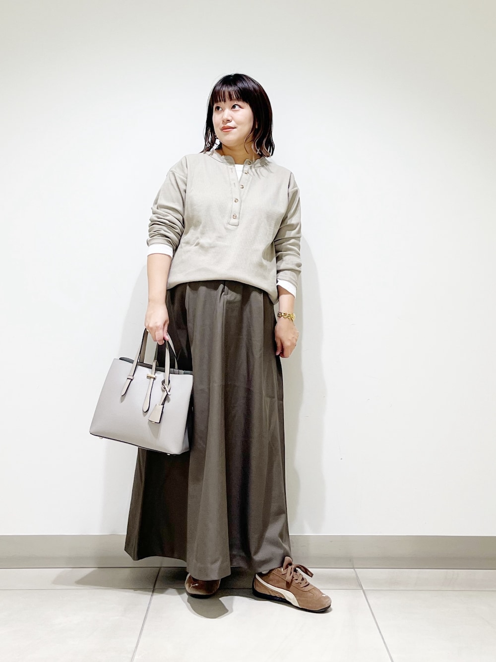 ベージュ系のTシャツ/カットソー、ブラウン系のスカート、グレー系のトートバッグを着用したレディースの秋コーディネートの1枚目の写真