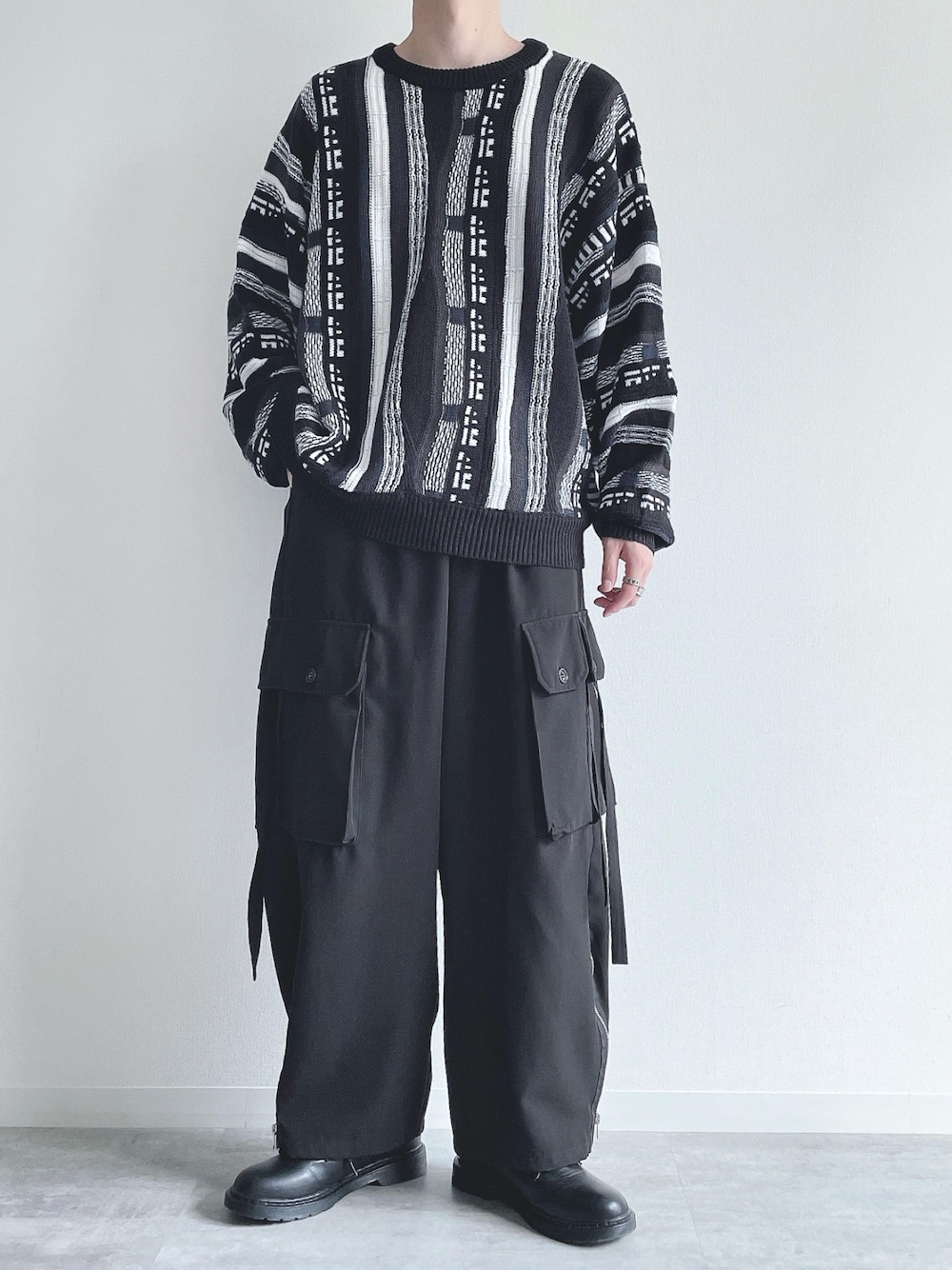 ブラック系のニット/セーター、ブラック系のカーゴパンツ、ブラック系のスニーカーを着用したメンズの秋コーディネートの1枚目の写真