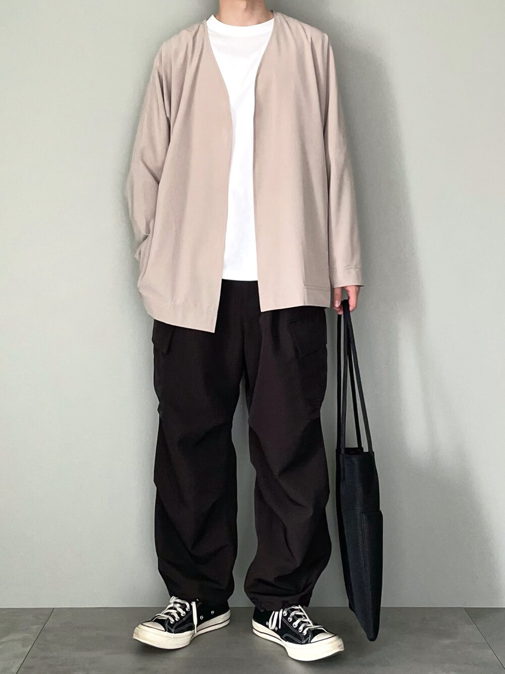 ベージュ系のカーディガン/ボレロ、ホワイト系のTシャツ/カットソー、ブラック系のカーゴパンツを着用したメンズの春コーディネートの1枚目の写真