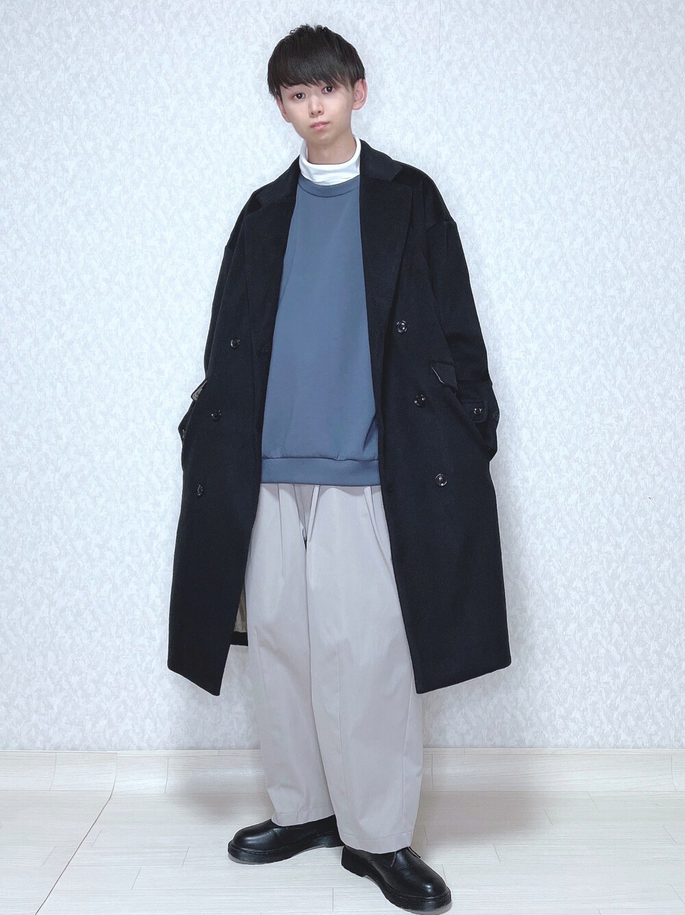 ブラック系のチェスターコート、ホワイト系のTシャツ/カットソー、ブルー系のトップスを着用したメンズの冬コーディネートの1枚目の写真