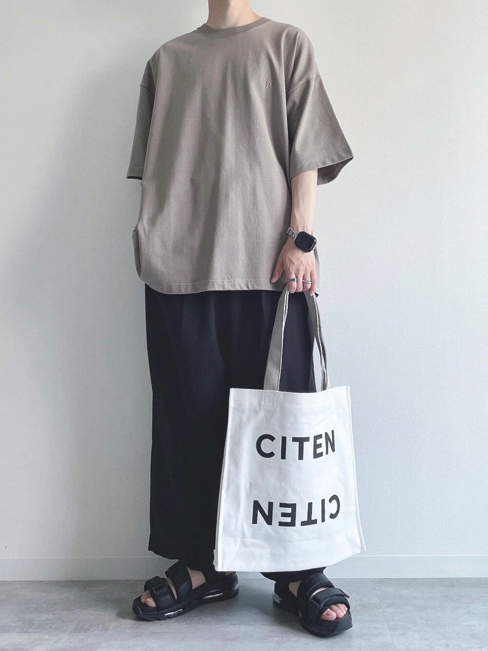 ベージュ系のTシャツ/カットソー、ブラック系のスラックス、ブラック系のサンダルを着用したメンズの夏コーディネートの1枚目の写真