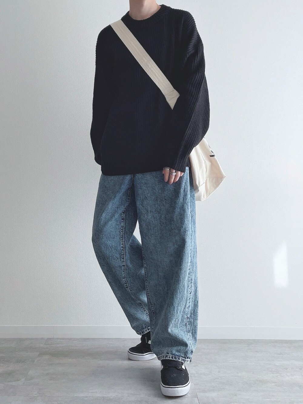 ブラック系のニット/セーター、ブルー系のパンツ、ブラック系のスニーカーを着用したメンズの冬コーディネートの1枚目の写真