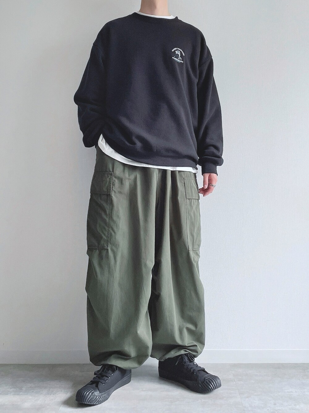 ブラック系のスウェット、ホワイト系のTシャツ/カットソー、グリーン系のカーゴパンツを着用したメンズの春コーディネートの1枚目の写真