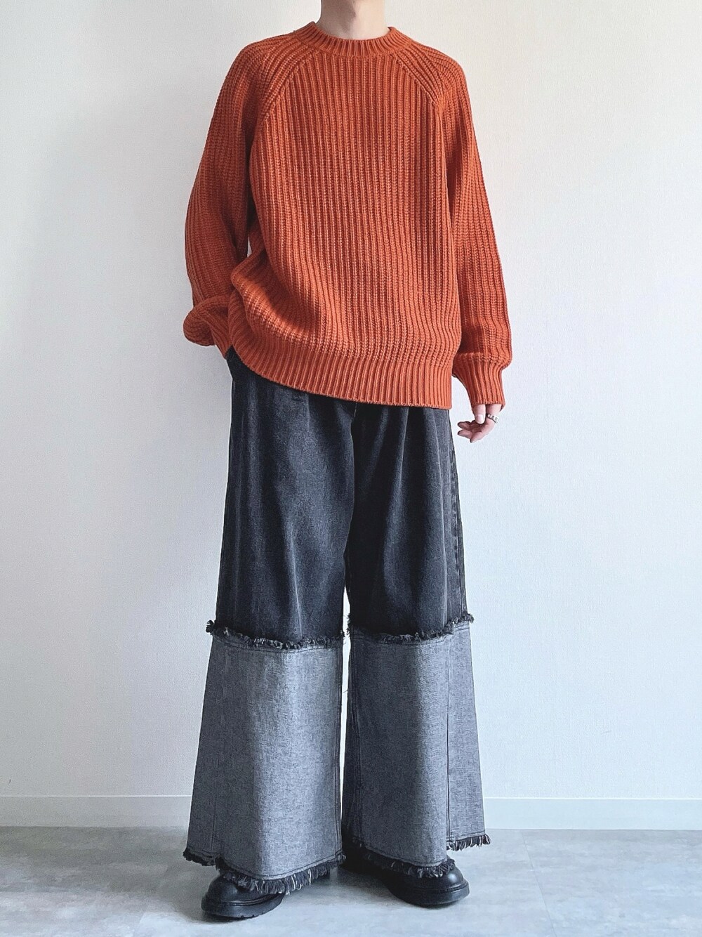 オレンジ系のトップス、ブラック系のデニムパンツ、ブラック系のスニーカーを着用したメンズの冬コーディネートの1枚目の写真