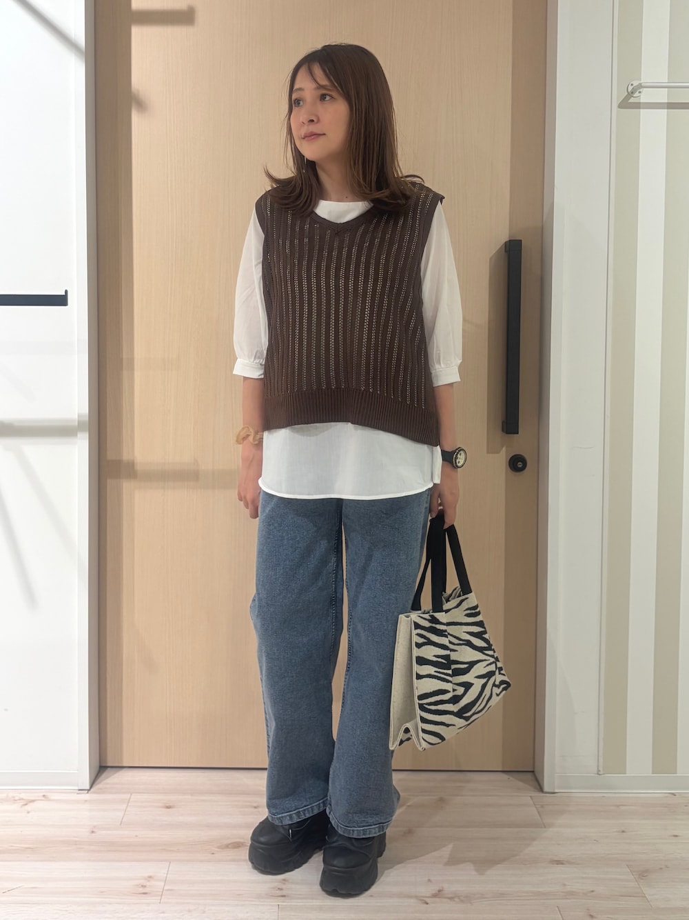 ブルー系のデニムパンツ、ブラック系のトートバッグを着用したレディースの秋コーディネートの1枚目の写真
