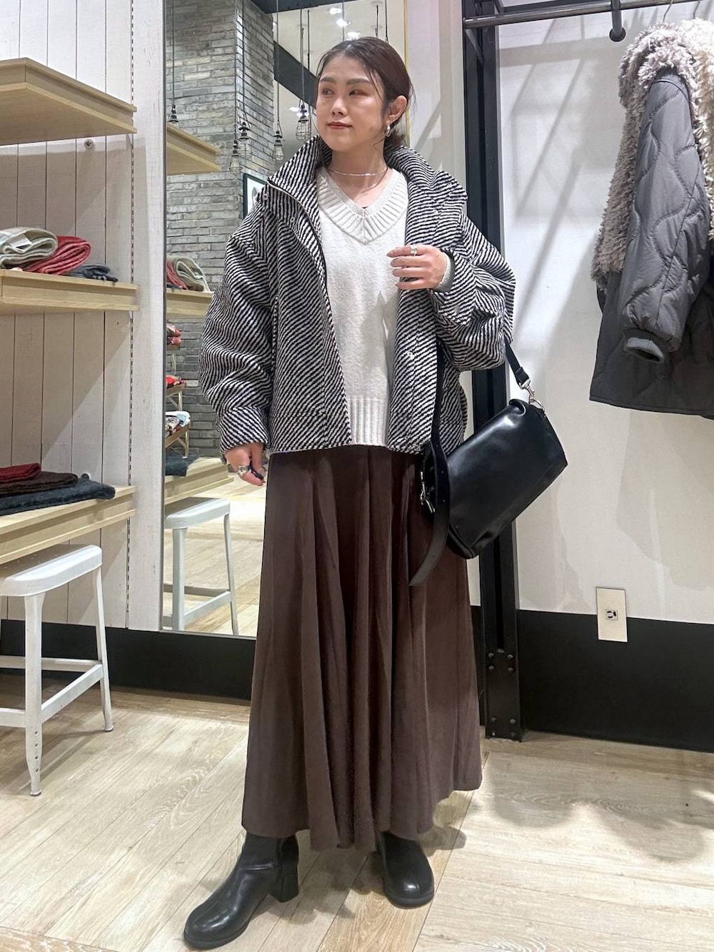 ブラック系のショルダーバッグ、ホワイト系のニット/セーター、ブラック系のブルゾンを着用したレディースの冬コーディネートの1枚目の写真