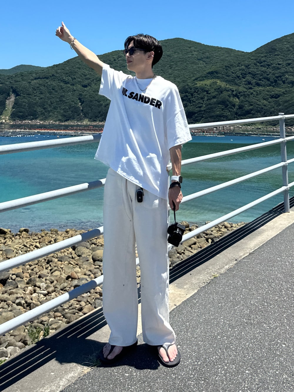 ホワイト系のTシャツ/カットソー、ホワイト系のスラックス、ブラック系のサンダルを着用したメンズの夏コーディネートの1枚目の写真