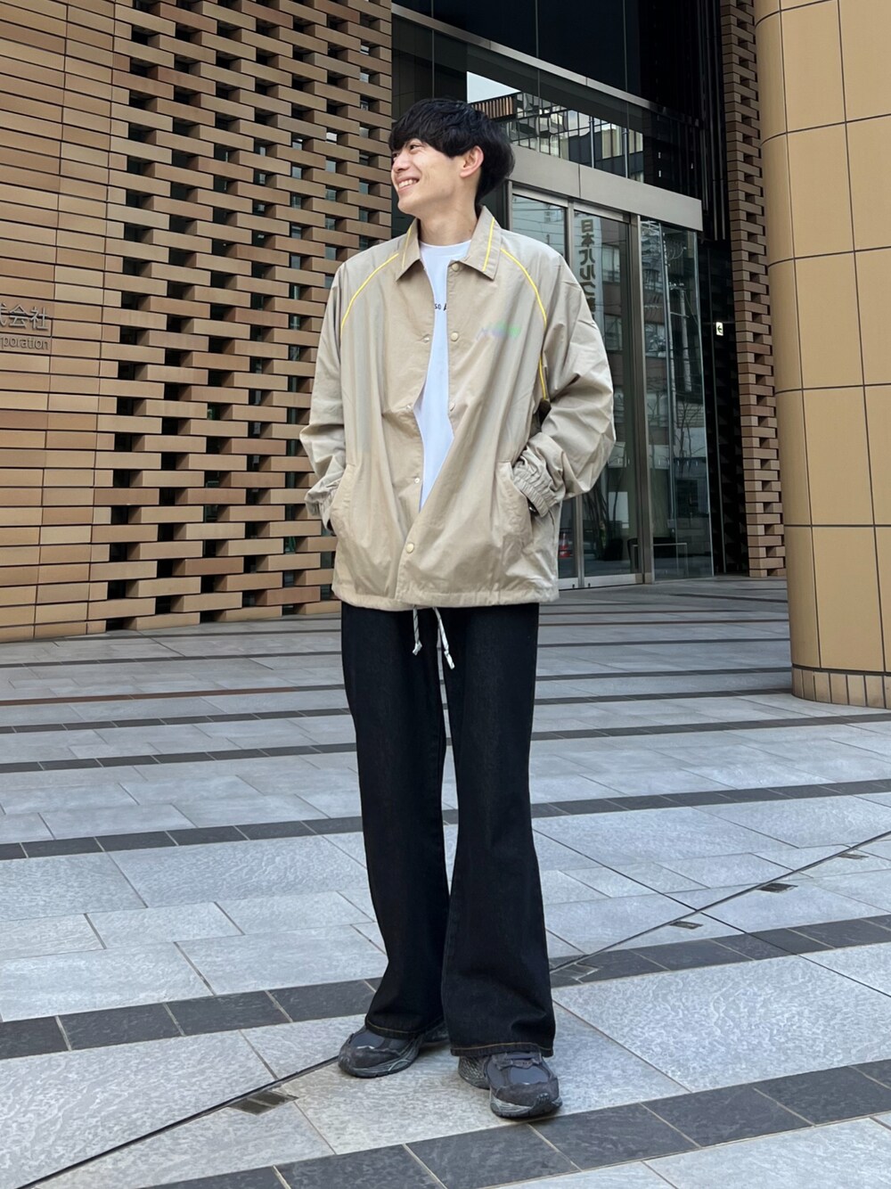 ブラック系のデニムパンツ、ベージュ系のナイロンジャケット、ホワイト系のTシャツ/カットソーを着用したメンズの冬コーディネートの1枚目の写真