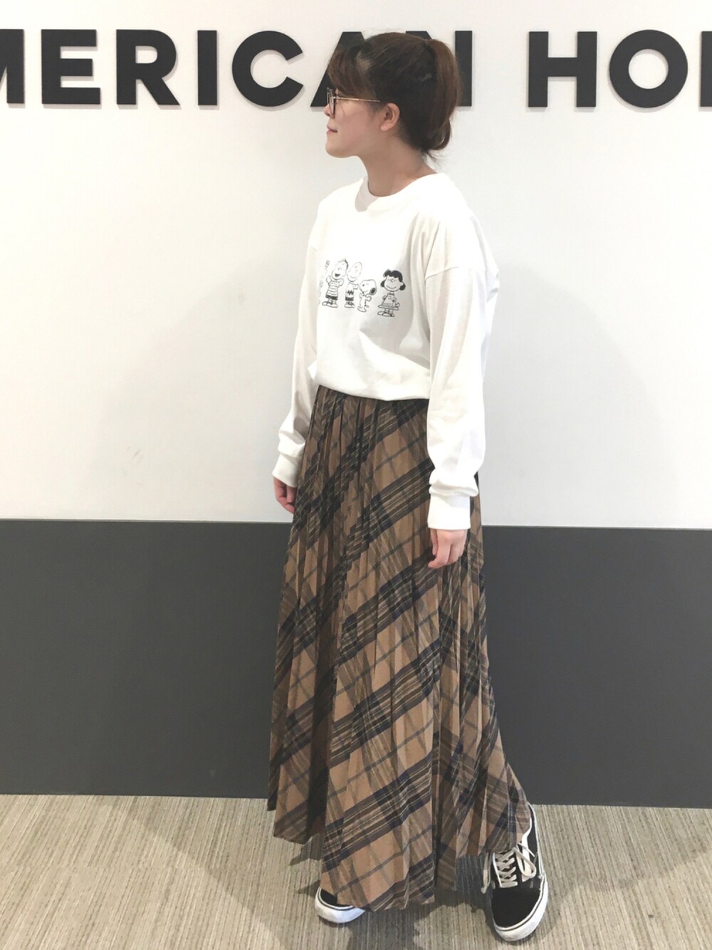 ブラック系のスニーカー、ホワイト系のTシャツ/カットソー、ベージュ系のスカートを着用したレディースの秋コーディネートの1枚目の写真