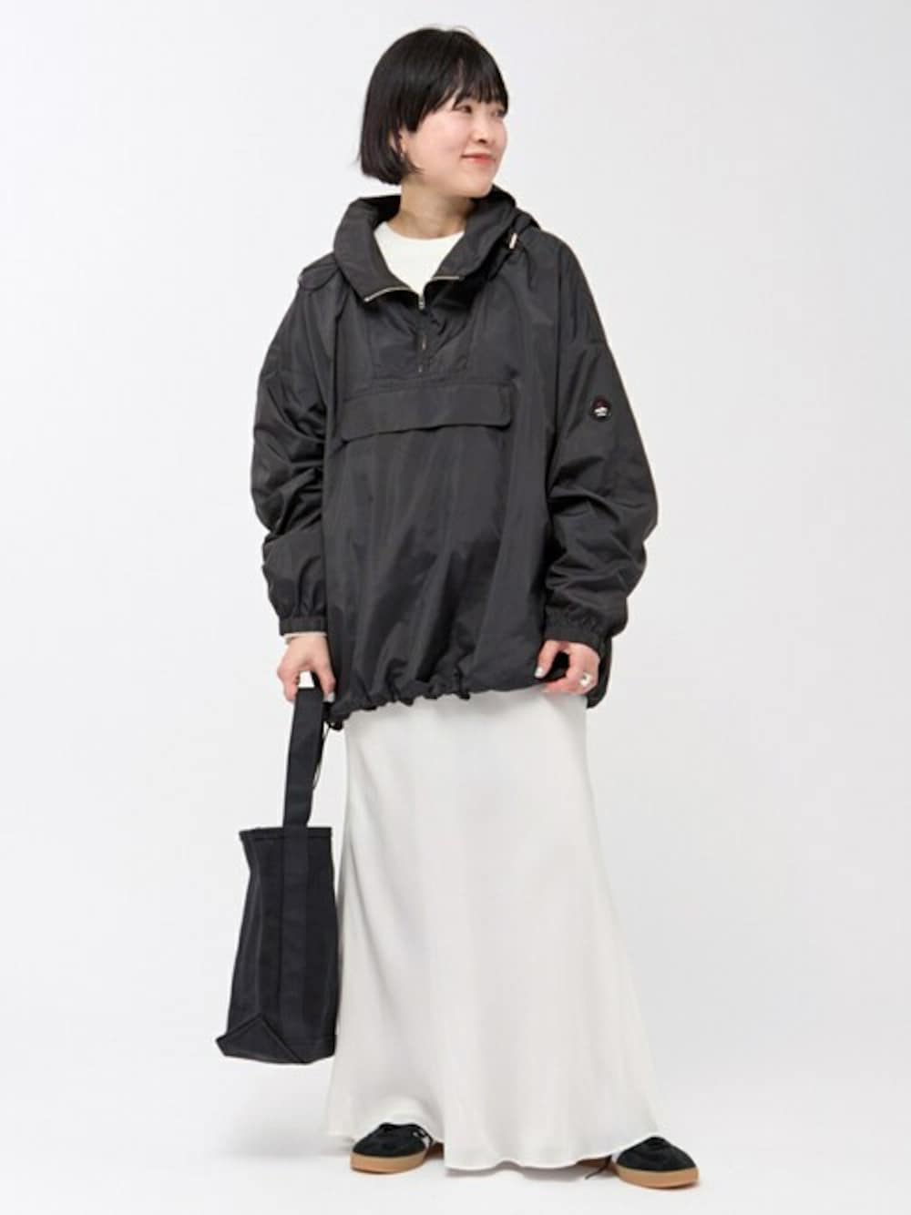 ブラック系のナイロンジャケット、ホワイト系のスカート、ホワイト系のニット/セーターを着用したレディースの冬コーディネートの1枚目の写真