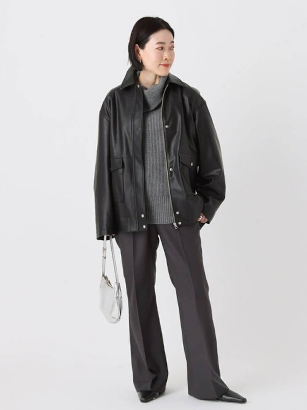 ブラック系のライダースジャケット、グレー系のニット/セーター、グレー系のスラックスを着用したレディースの秋コーディネートの1枚目の写真