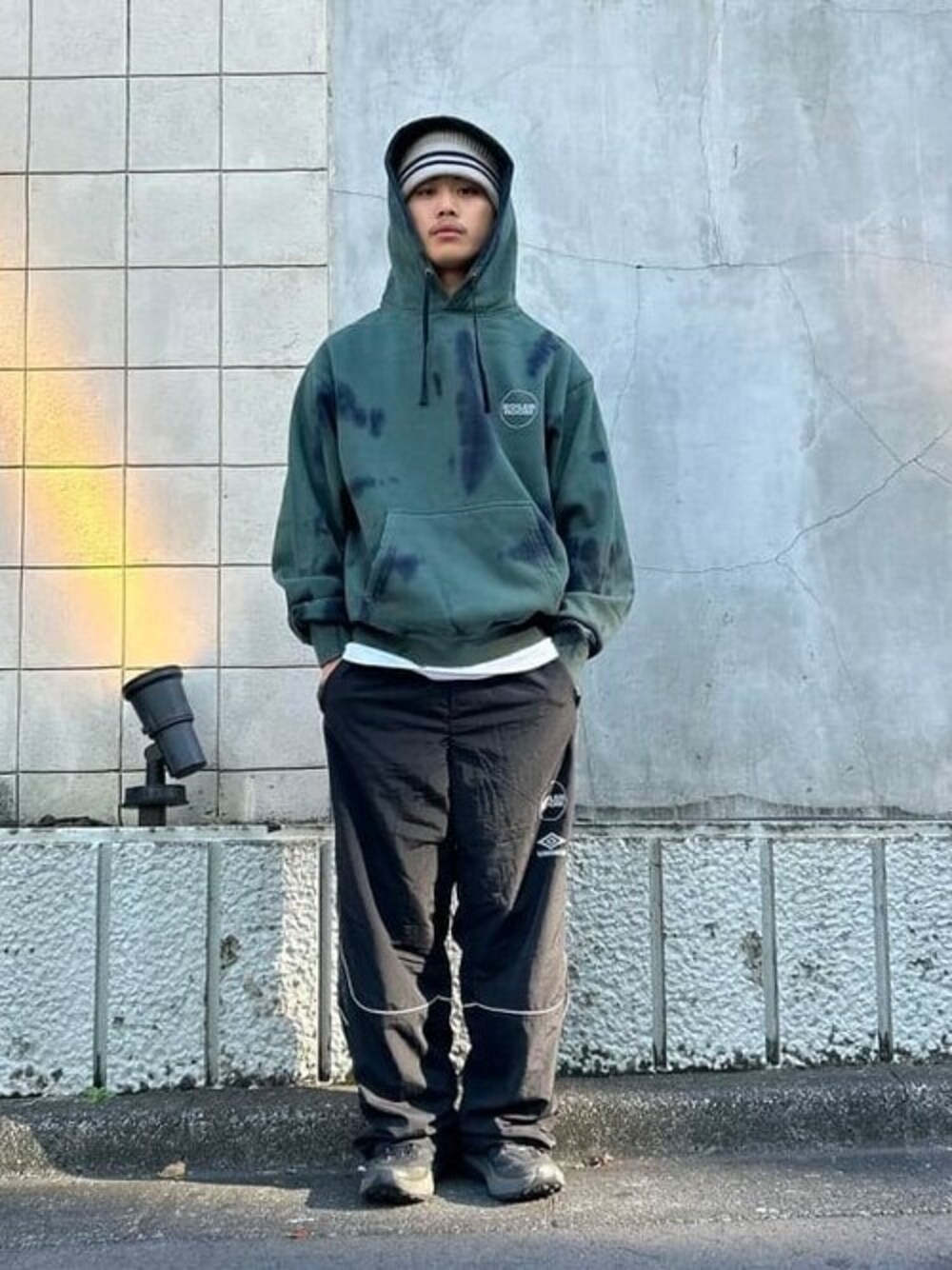 グリーン系のスウェット、ベージュ系のハットを着用したメンズの秋コーディネートの1枚目の写真