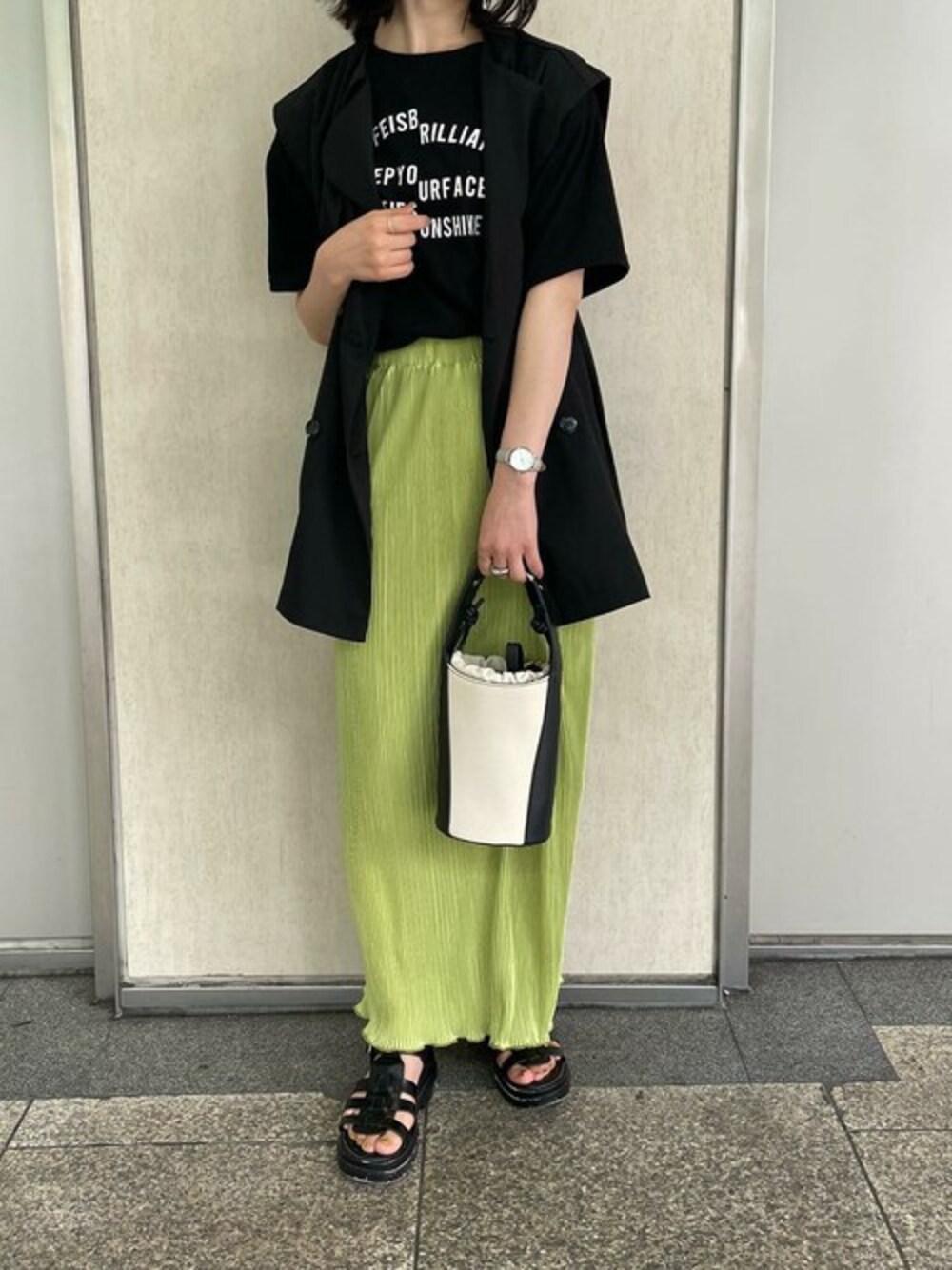ブラック系のTシャツ/カットソー、ブラック系のベスト、グリーン系のスカートを着用したレディースの夏コーディネートの1枚目の写真