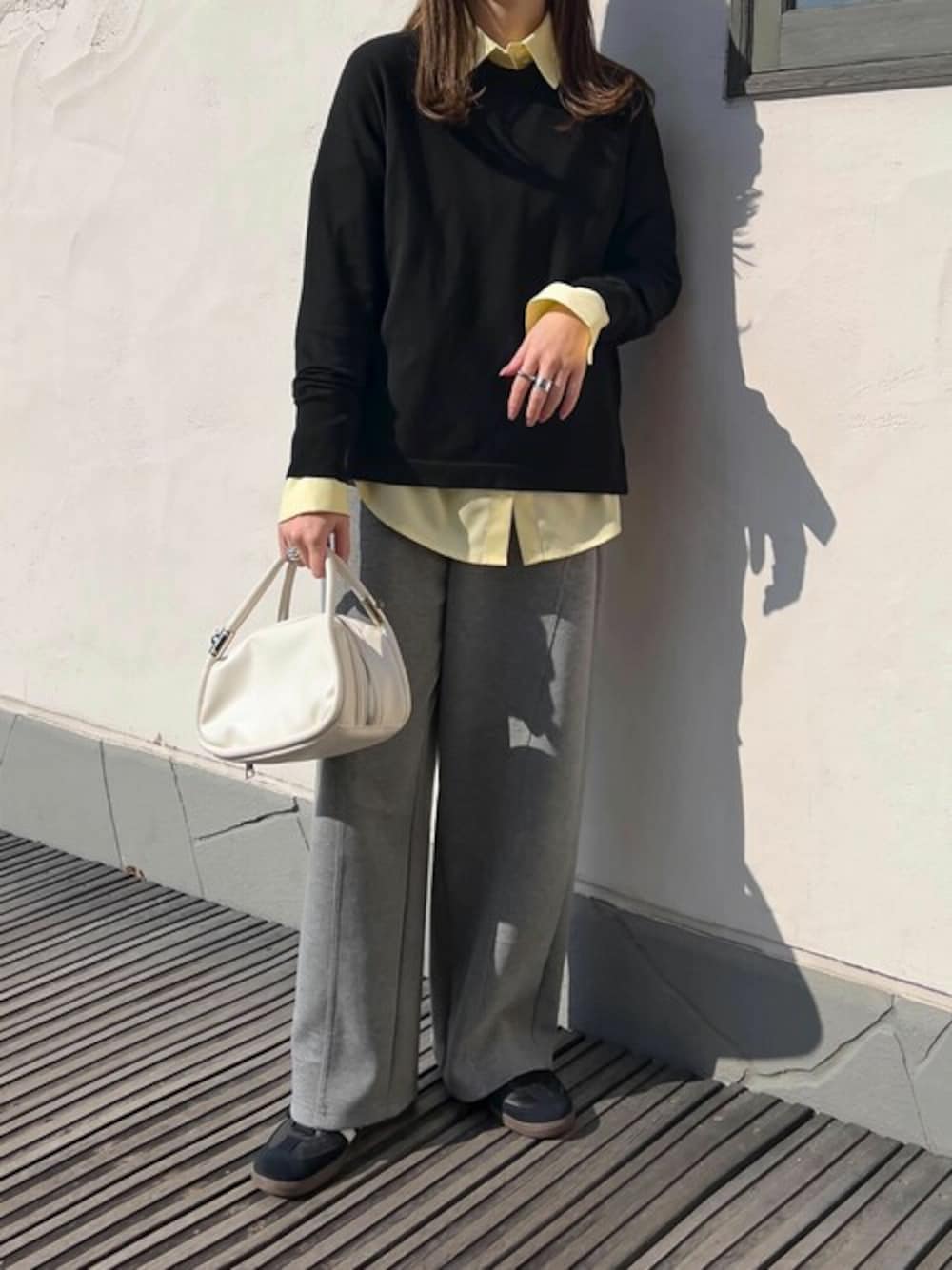 イエロー系のシャツ/ブラウス、ブラック系のニット/セーター、グレー系のスウェットパンツを着用したレディースの春コーディネートの1枚目の写真