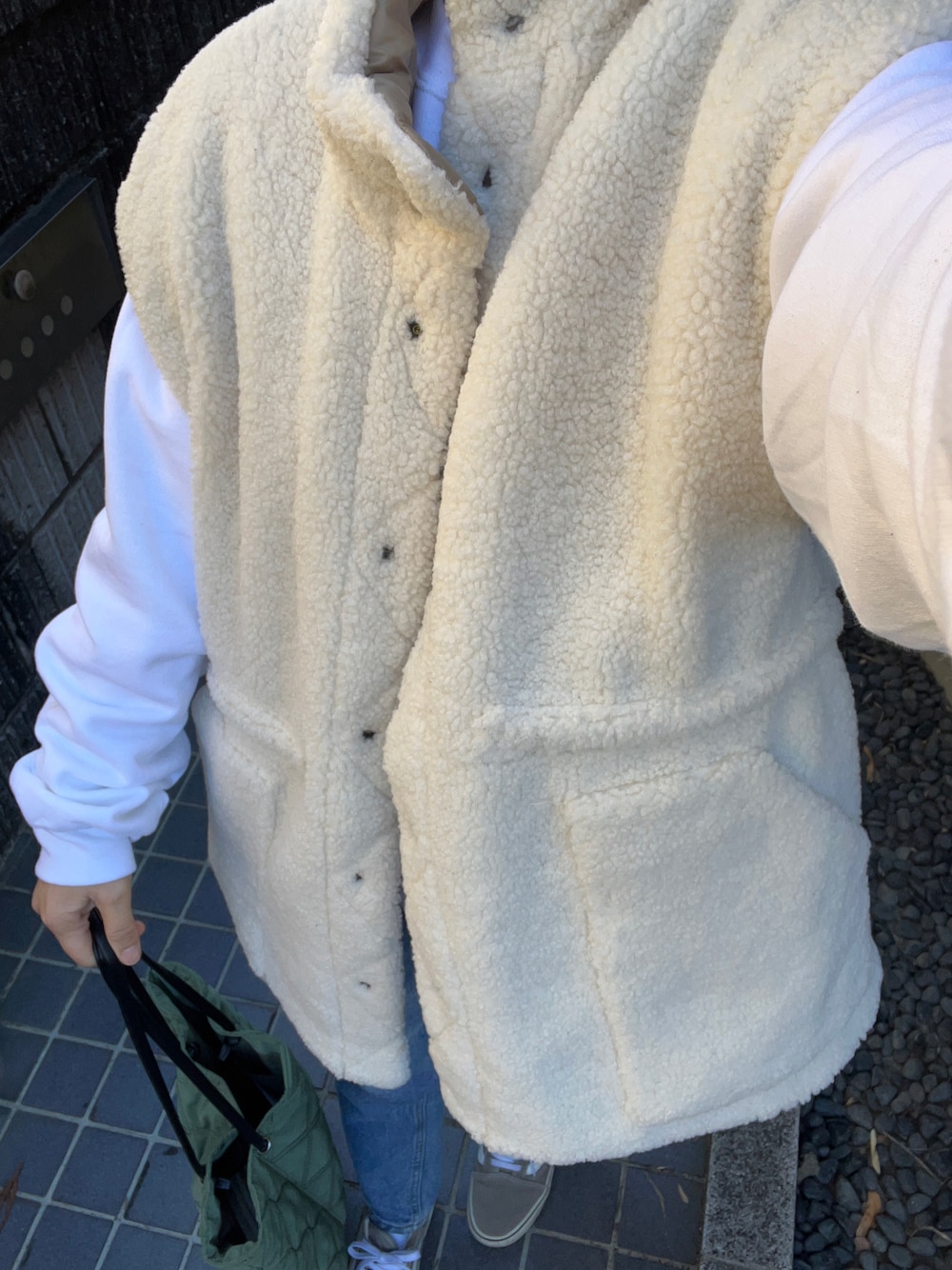 イエロー系のダウンベスト、ホワイト系のスウェット、ホワイト系のTシャツ/カットソーを着用したレディースの冬コーディネートの1枚目の写真