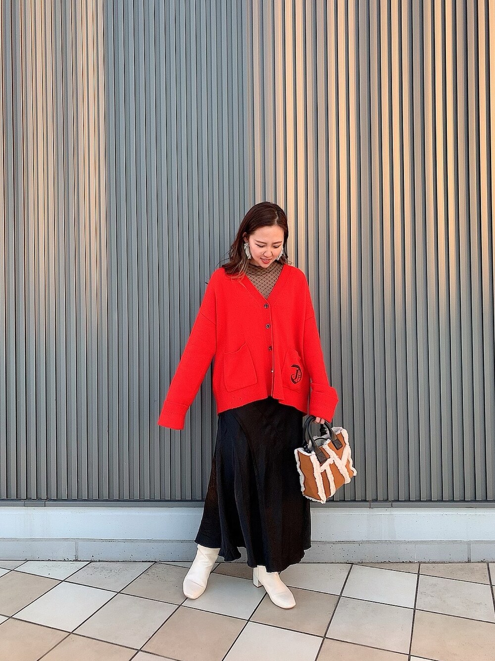 レッド系のカーディガン/ボレロ、ブラウン系のトートバッグ、ブラック系のスカートを着用したレディースの秋コーディネートの1枚目の写真