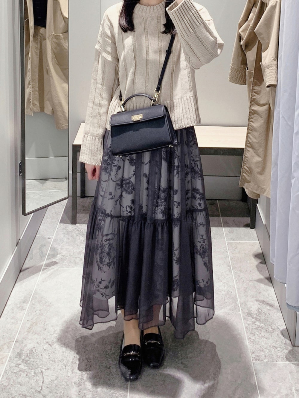 ブラック系のスカート、ベージュ系のニット/セーター、ブラック系のショルダーバッグを着用したレディースの秋コーディネートの1枚目の写真