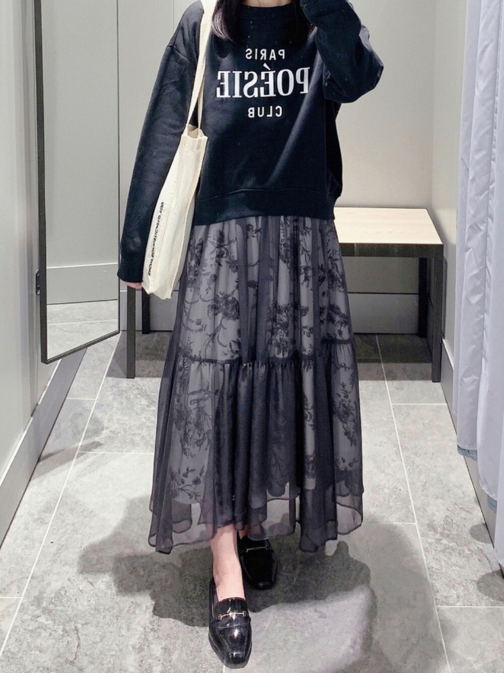 ブラック系のスウェット、ブラック系のスカート、ブラック系のレインシューズを着用したレディースの秋コーディネートの1枚目の写真