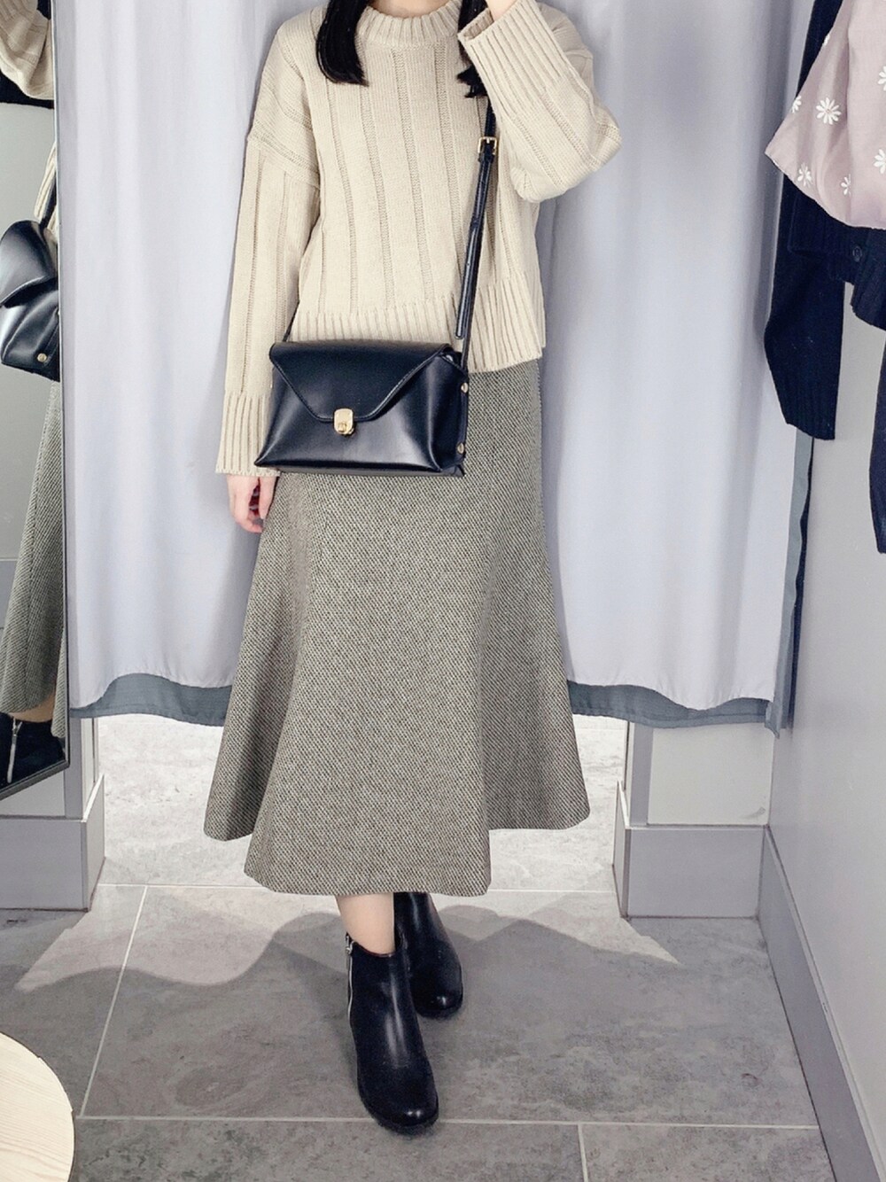 ブラック系のショルダーバッグ、ベージュ系のスカート、ブラック系のブーツを着用したレディースの秋コーディネートの1枚目の写真