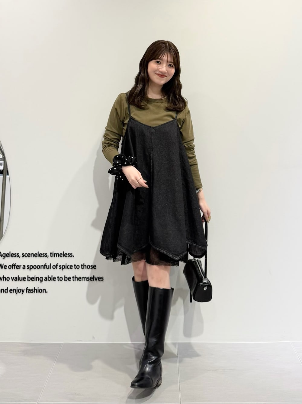 ブラック系のワンピース、グリーン系のTシャツ/カットソー、ブラック系のショルダーバッグを着用したレディースの春コーディネートの1枚目の写真