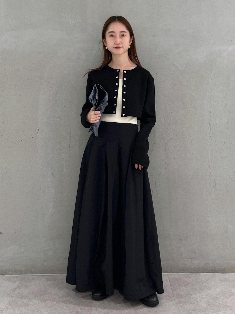 ブラック系のカーディガン/ボレロ、ホワイト系のキャミソール、ブラック系のスカートを着用したレディースの秋コーディネートの1枚目の写真