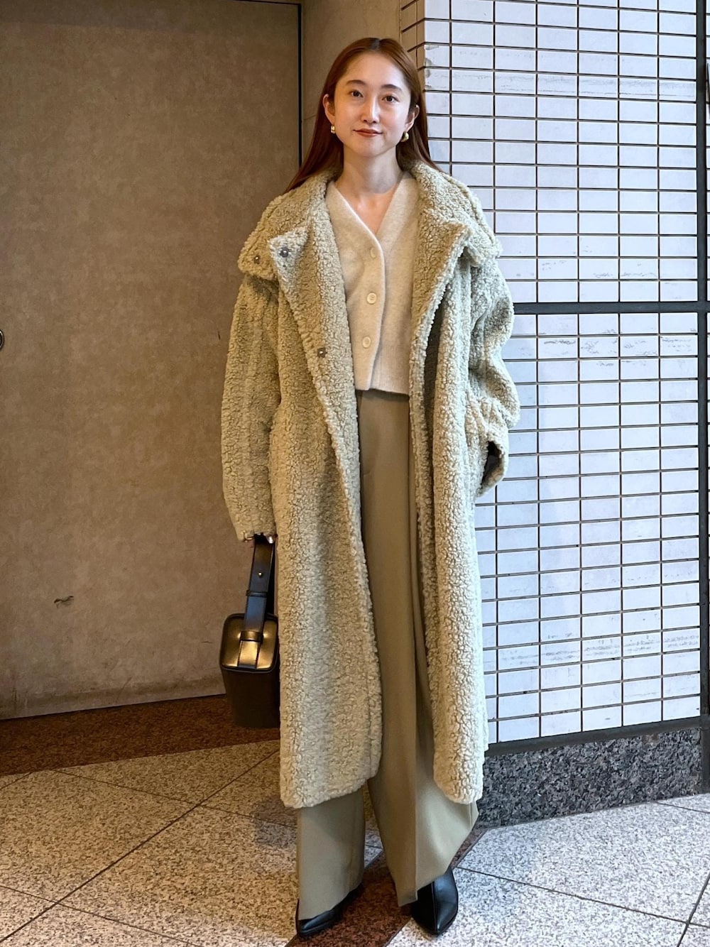 ブラック系のブーツ、ホワイト系のカーディガン/ボレロ、グリーン系のその他アウターを着用したレディースの冬コーディネートの1枚目の写真