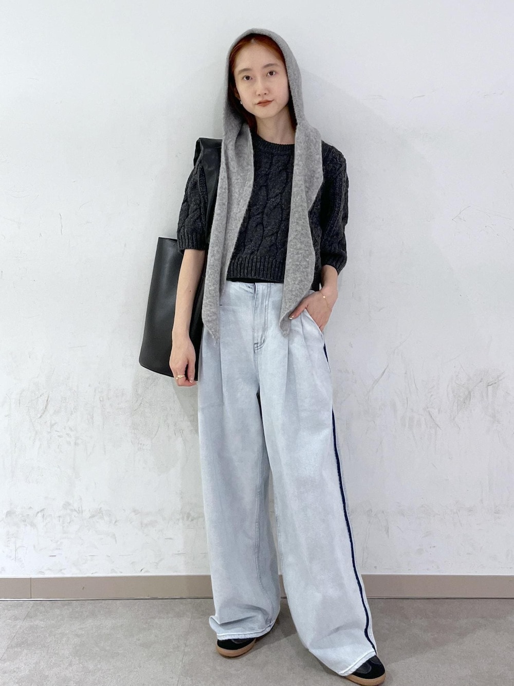 ブルー系のデニムパンツ、ブラック系のショルダーバッグ、グレー系のニット/セーターを着用したレディースの秋コーディネートの1枚目の写真