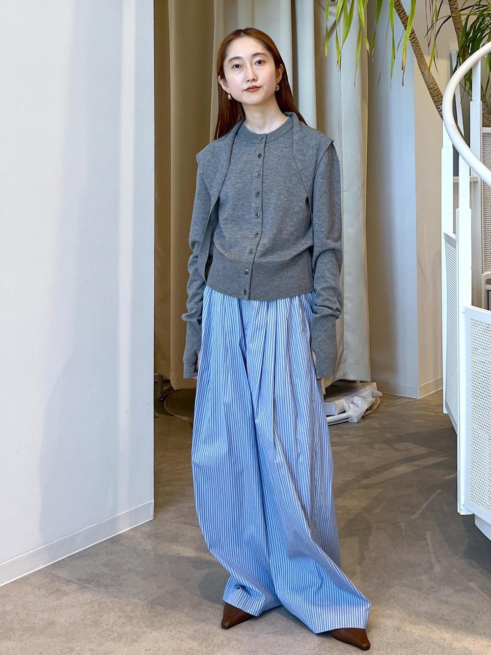 ブラウン系のサンダル、ブルー系のスラックス、グレー系のカーディガン/ボレロを着用したレディースの秋コーディネートの1枚目の写真