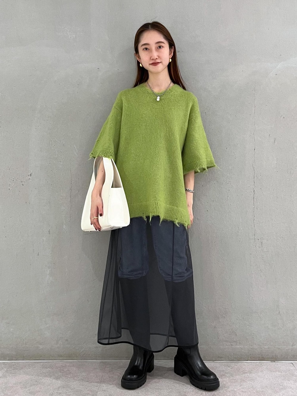 ブラック系のブーツ、ホワイト系のハンドバッグ、ブルー系のデニムパンツを着用したレディースの秋コーディネートの1枚目の写真